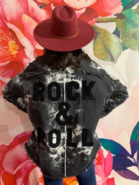 Person wearing a red hat and a dark “Rock & Roll” denim jacket